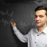 Nauczyciel wyjaśnia, czym jest logarytm, pisząc na tablicy wzory matematyczne.