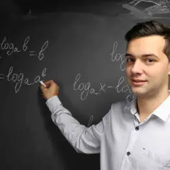 Nauczyciel wyjaśnia, czym jest logarytm, pisząc na tablicy wzory matematyczne.