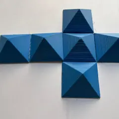 Niebieskie, drukowane 3D piramidy ułożone w kształt krzyża. Różnica sześcianów widoczna w ich trójwymiarowej formie.