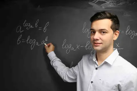 Nauczyciel wyjaśnia, czym jest logarytm, pisząc na tablicy wzory matematyczne.