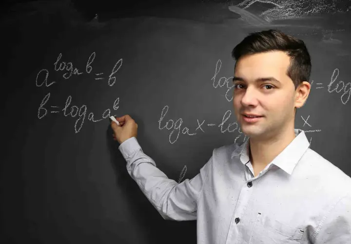 Nauczyciel wyjaśnia, czym jest logarytm, pisząc na tablicy wzory matematyczne.