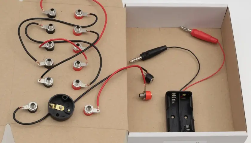 Zestaw do eksperymentów z elektrycznością dla klasy 6: przewody, gniazda, uchwyt na baterie i wtyczki.