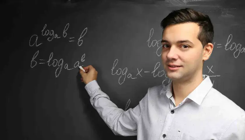 Nauczyciel wyjaśnia, czym jest logarytm, pisząc na tablicy wzory matematyczne.