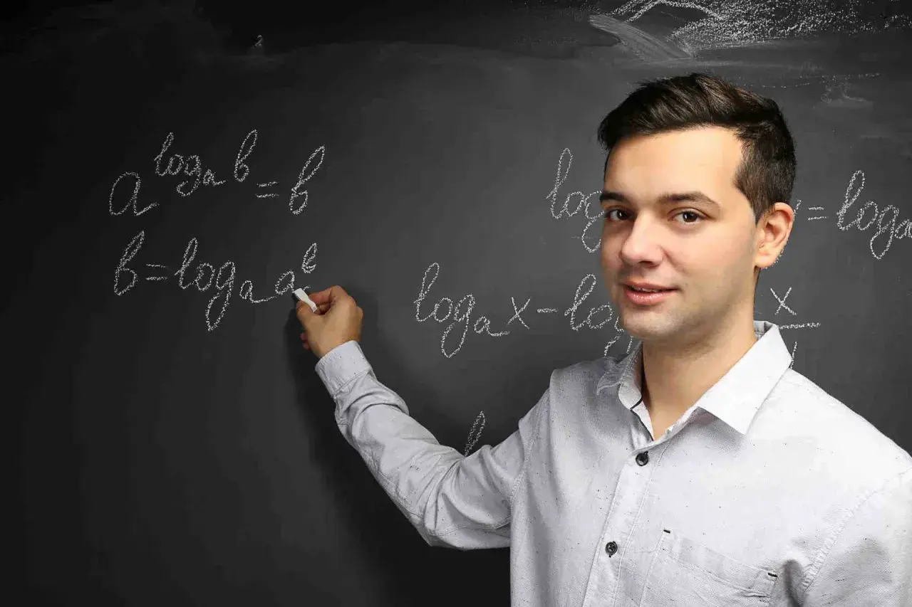 Nauczyciel wyjaśnia, czym jest logarytm, pisząc na tablicy wzory matematyczne.